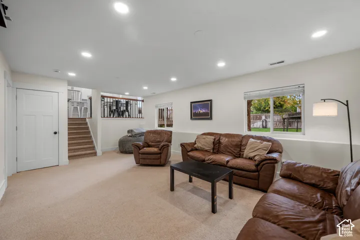 Recessed ceiling lighting, light-colored carpeting, white interior doors, white trim, and a wood-finish staircase with black railing