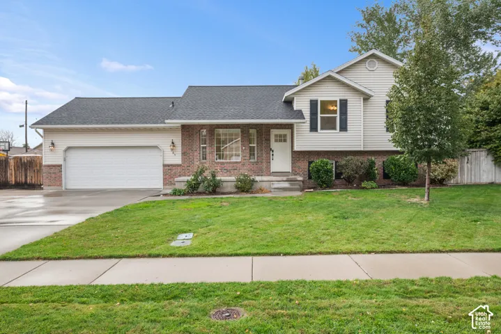 Brick and siding exterior with a two-car garage, mature front yard landscaping, and a concrete driveway