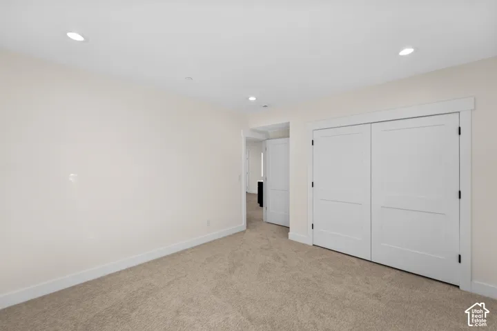 Recessed lighting illuminates the carpeted flooring and light-toned walls