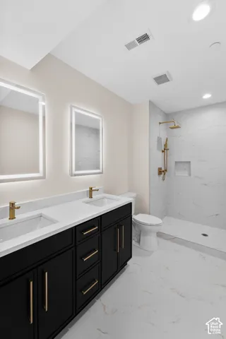 Dual vanity with black cabinetry, gold-tone hardware, and integrated sinks