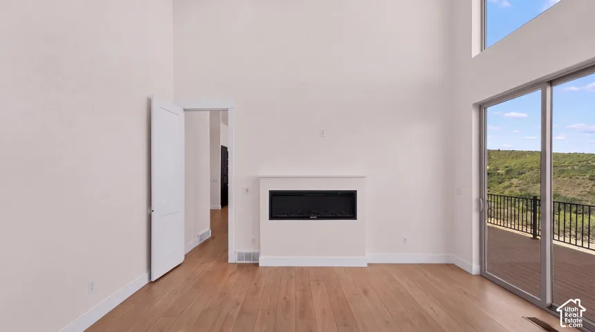 High ceilings, wood-finish flooring, built-in fireplace, sliding glass doors, and elevated outdoor deck