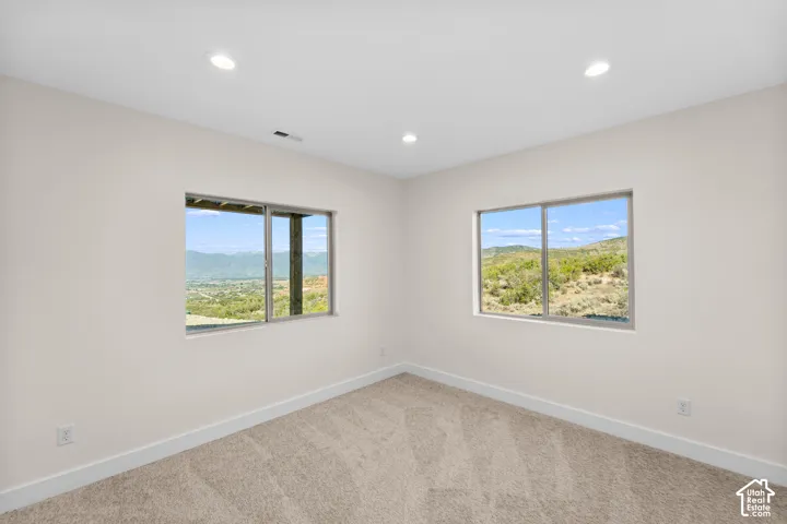 Recessed lighting, neutral wall paint, two large windows, and carpet flooring