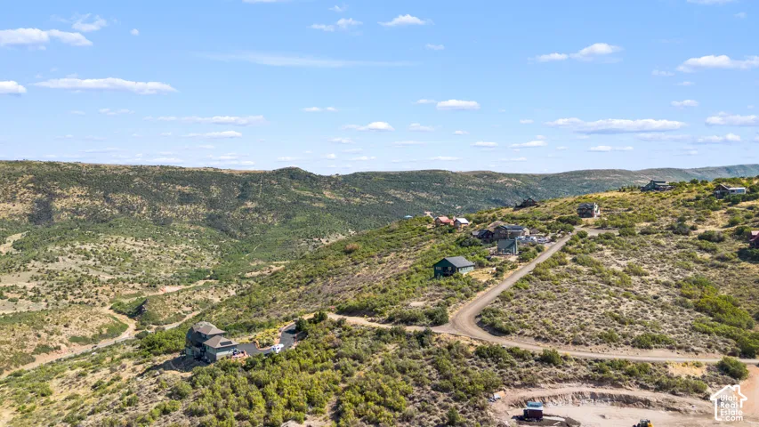 Expansive hillside property featuring multiple residences, a winding unpaved road, and distant mountain backdrops