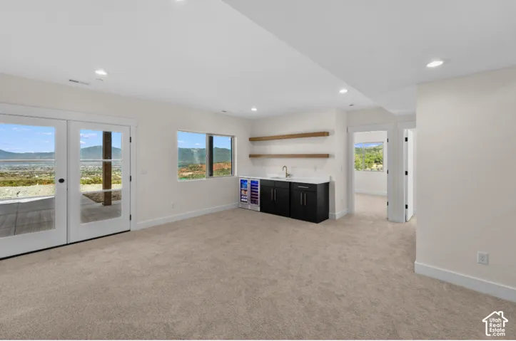 Recessed lighting, carpet flooring, and a built-in wet bar with a sink, black cabinetry, and open shelving
