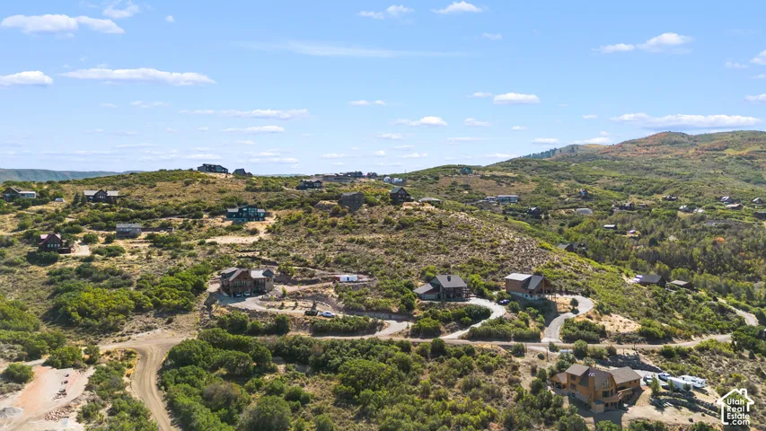 Expansive hillside setting featuring multiple residences, natural landscaping, and paved winding roads