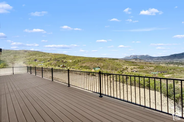 Expansive outdoor deck featuring composite decking, black metal railings, and a mountainous landscape backdrop