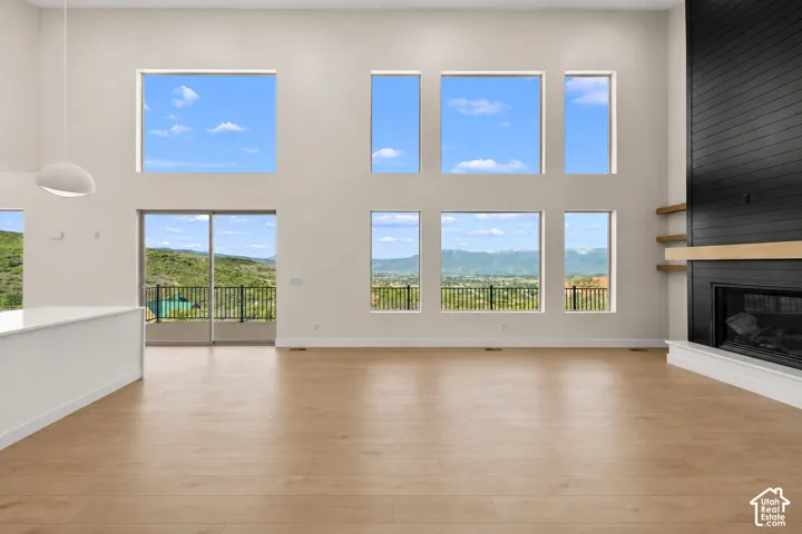 High ceilings with expansive windows, light wood-finish flooring, a contemporary fireplace with black shiplap surround, and a white countertop