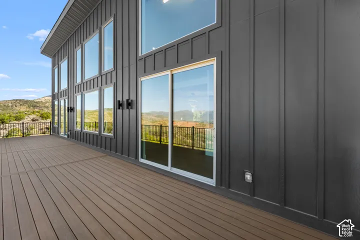 Expansive deck with composite wood-finish flooring, featuring a black metal railing and a dark vertical-panel exterior