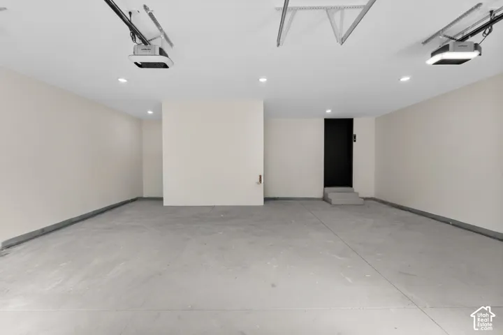 Spacious garage featuring concrete flooring, recessed lighting, and dual automatic garage door openers