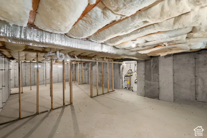 Unfinished basement featuring concrete walls and flooring, exposed ceiling insulation, and visible plumbing