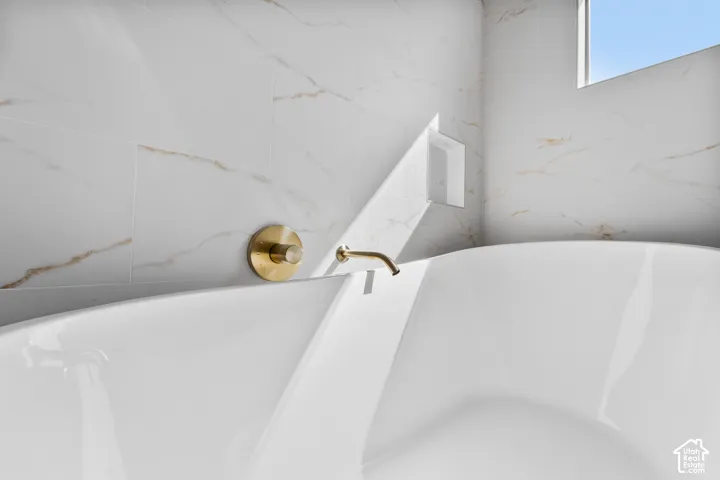 Bathtub with a brass-finish faucet, wall-mounted control knob, and tiled surround