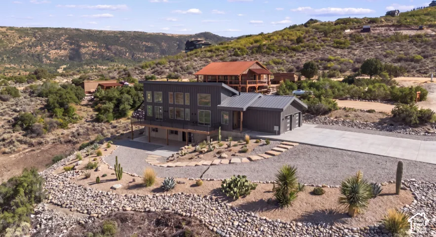 Modern exterior with multiple large windows, attached two-car garage, concrete driveway, and desert-style landscaping