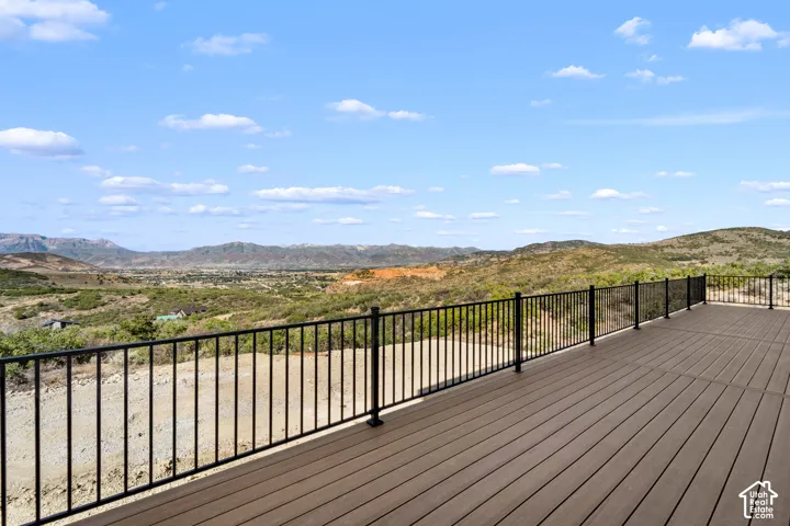 Expansive outdoor deck with composite decking, black metal railing, and a mountainous landscape backdrop