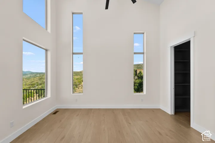 High ceilings with multiple large windows, wood-finish flooring, and built-in shelving in an open doorway