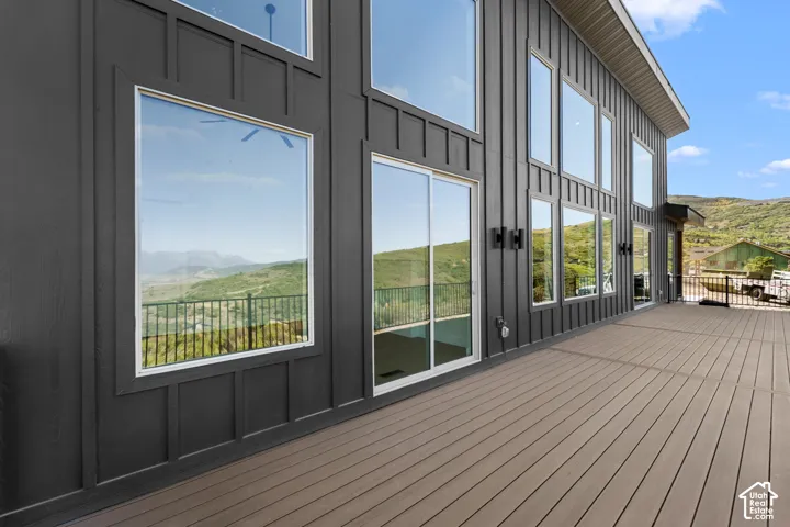 Expansive outdoor decking, modern board and batten siding, multiple large windows, and sliding glass doors