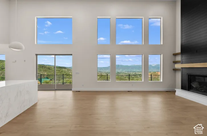 Vaulted ceilings with multiple windows, wood-finish flooring, and a contemporary fireplace with a black shiplap surround