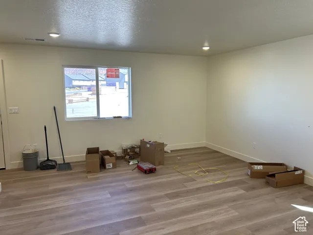 Recessed lighting, wood-finish flooring, white walls, and a large window