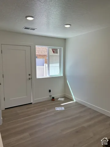 Recessed ceiling lighting, wood-finish flooring, white trim, and a window with a white frame