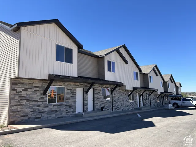 Multi-unit property with a stone and vertical siding facade, featuring gable roofs and dark trim accents