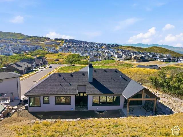 Modern residential home featuring a distinctive pitched roof with dark asphalt shingles, clean-lined architecture with contrasting light and dark exterior finishes, multiple large windows providing natural light, and a sloped green roof section