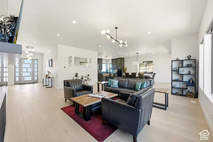 Expansive open-concept living area featuring light wood-finish flooring, recessed lighting, and a contemporary chandelier