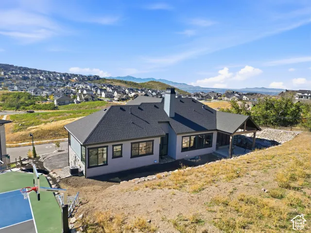 Property featuring a covered outdoor patio, a sports court, and a stone retaining wall