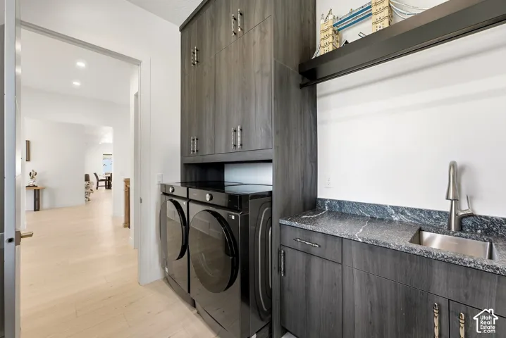 Laundry area featuring wood-finish cabinetry, built-in sink, and stone countertop