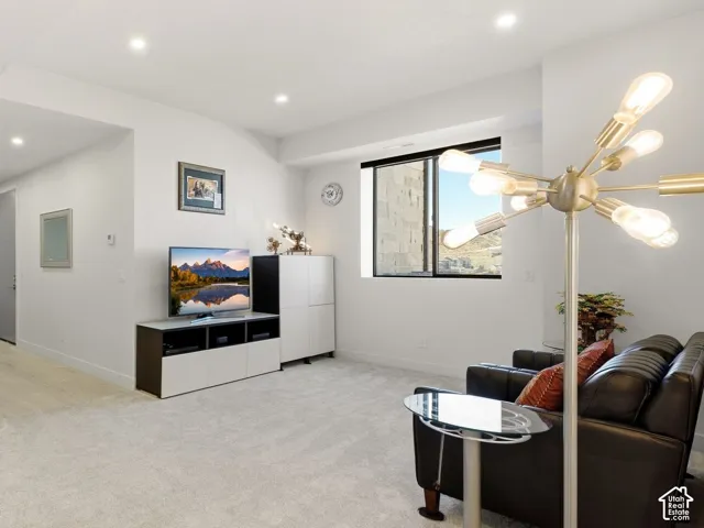 Recessed lighting, light-toned carpeting, wood-finish flooring, and a large window