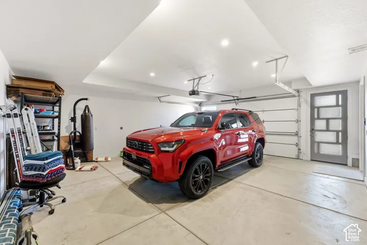 Spacious garage featuring a sectional garage door, recessed lighting, and a contemporary entry door with frosted glass panels