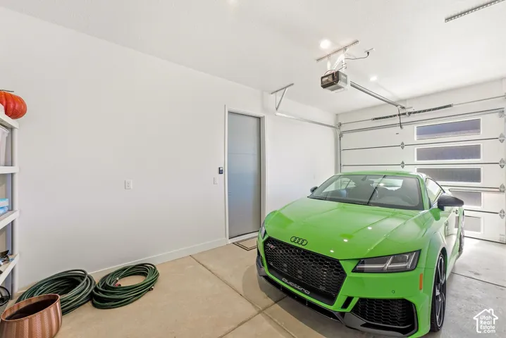 Attached garage with a modern sectional door featuring frosted windows, recessed lighting, and a neutral-toned concrete floor