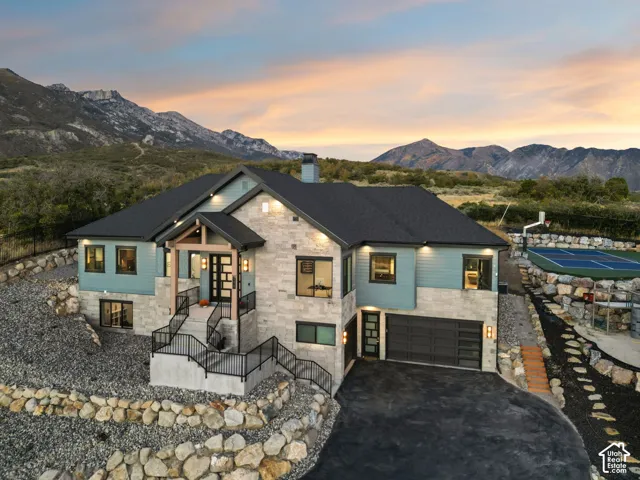 Contemporary exterior featuring a stone and siding facade, a black asphalt driveway, and a built-in sports court