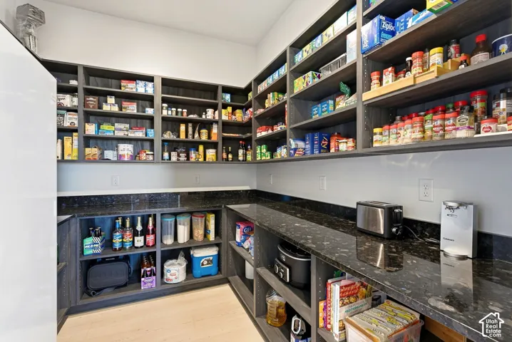 Built-in shelving, dark-finish cabinetry, extensive countertop space, wood-finish flooring, and integrated power outlets