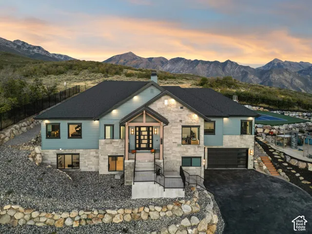 Contemporary exterior featuring varied siding, stone accents, a multi-pane front entry door, a multi-car garage, and an upper-level sports court