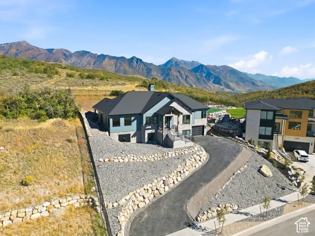 Modern exterior with a dark-pitched roof, light blue siding, stone accents, and a paved driveway