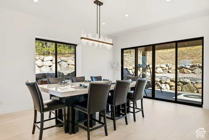 Light wood-finish flooring with a modern linear chandelier and recessed lighting