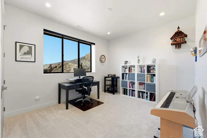 Recessed lighting, large window with outdoor scenery, light-toned carpeting, and white walls