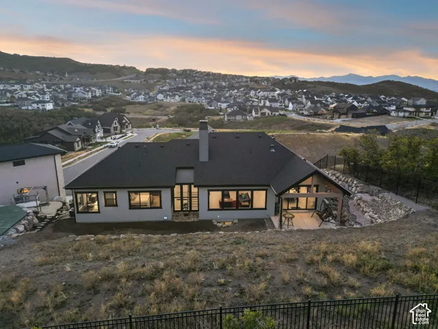 Contemporary residence featuring a dark shingle roof, light-toned exterior siding, and a covered outdoor patio with exposed beams