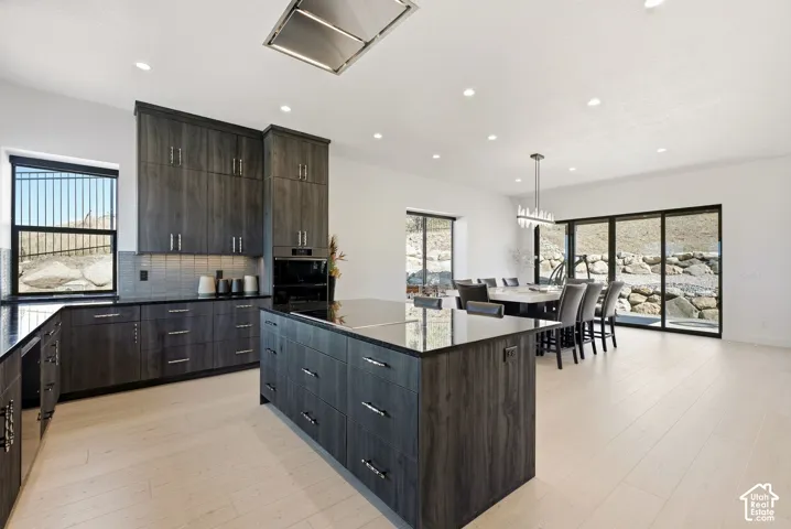 Open-concept kitchen featuring wood-finish cabinetry, black countertops, and a central island