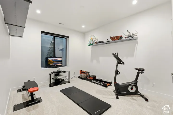 Recessed lighting, light-toned carpet, and a window with black trim