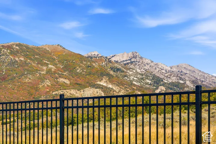 Black metal fence with mountain backdrop featuring varied terrain and natural foliage