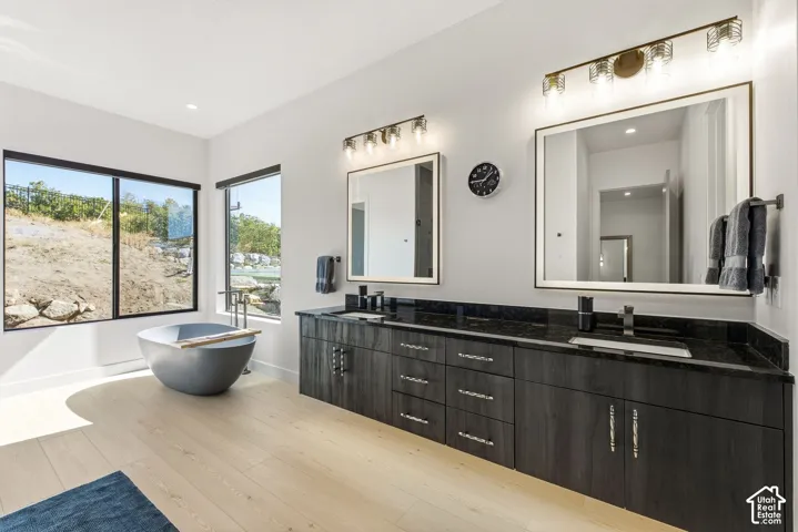 Dual vanity with dark wood-finish cabinetry, black countertops, and individual framed mirrors with integrated lighting