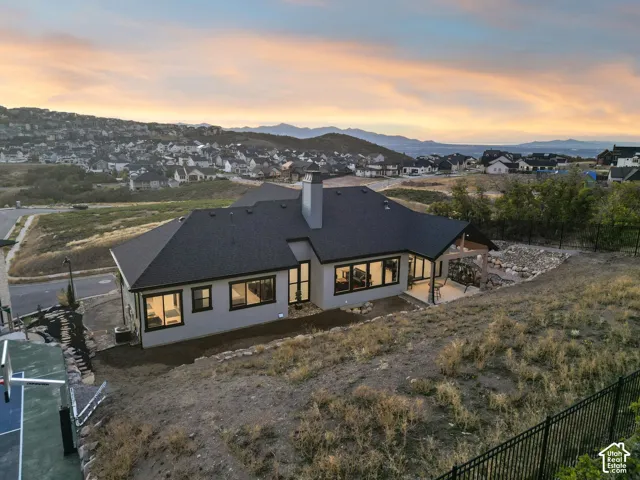 Contemporary architecture featuring a dark shingle roof, light-colored exterior, and an expansive covered patio