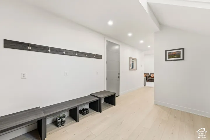 Recessed lighting illuminates wood-finish flooring and white walls