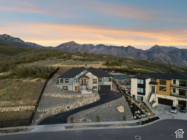 Contemporary residence featuring stone and siding exterior, a paved driveway, and extensive rock landscaping