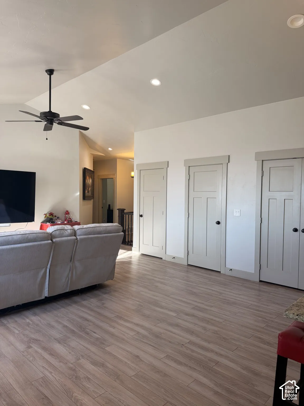 Vaulted ceiling with recessed lighting and a ceiling fan, wood-finish flooring, and white paneled doors
