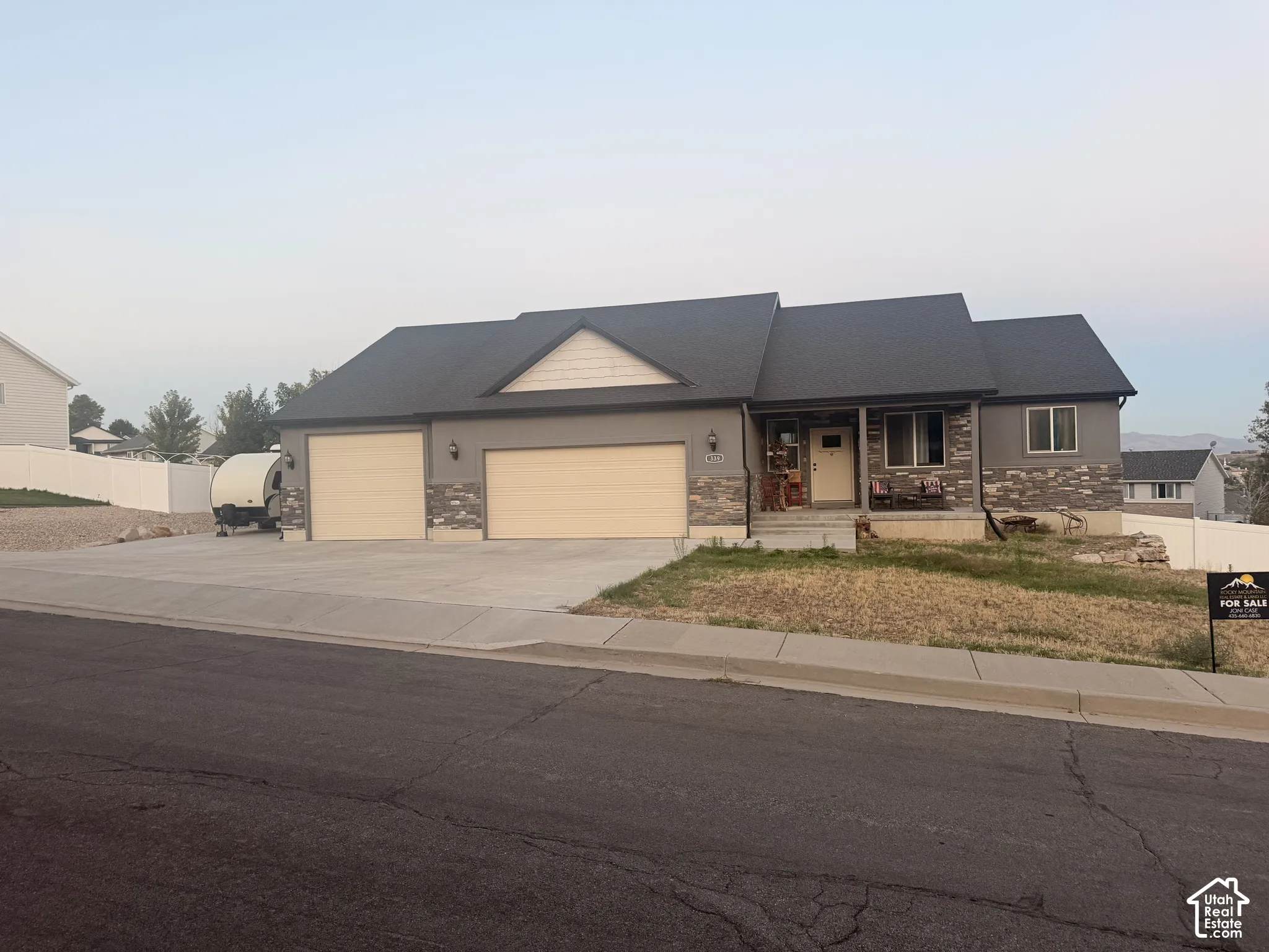 Stucco exterior with stone accenting, two-car garage, covered entry, and a paved driveway