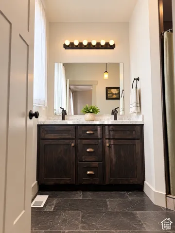 Dual sink vanity with dark wood-finish cabinetry, a light-toned countertop, and a large wall-mounted mirror