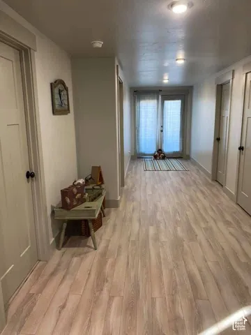 Recessed lighting illuminates the hallway with light wood-finish flooring and multiple paneled doors