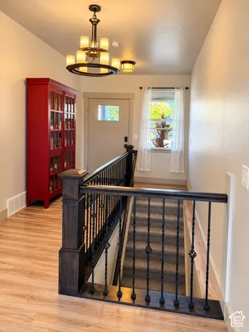 Wood-finish flooring, wrought iron stair railing, and a window with sheer coverings