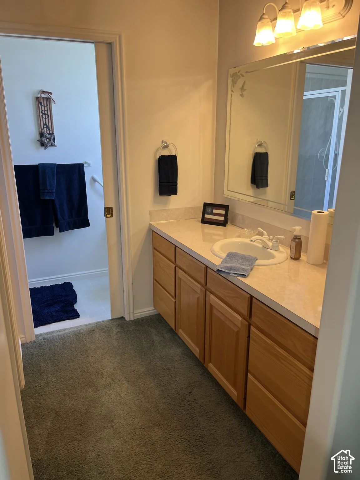 Vanity with wood-finish cabinetry, integrated sink, and light-colored countertop